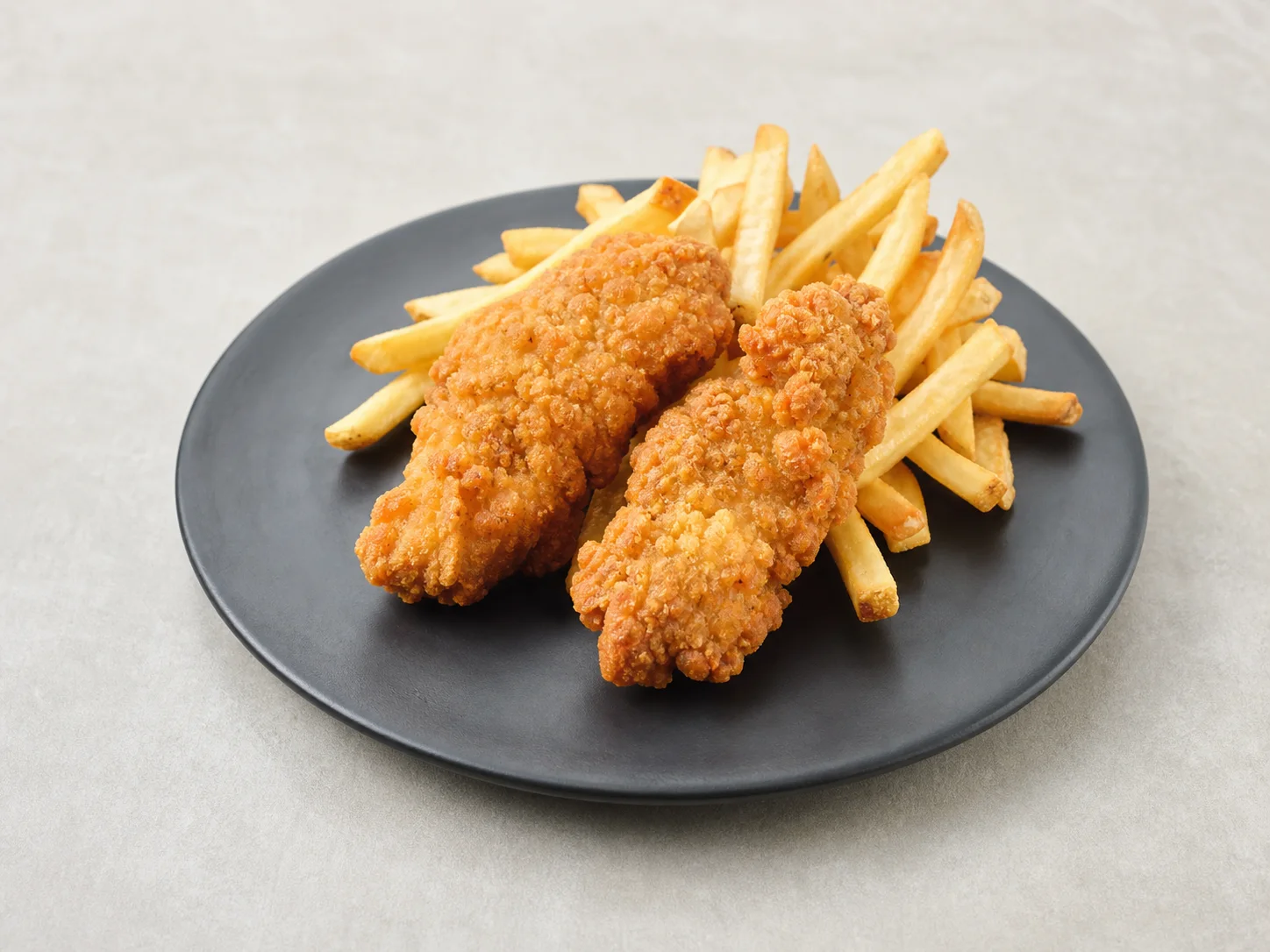 Golden chicken tenders with French fries on a dark plate