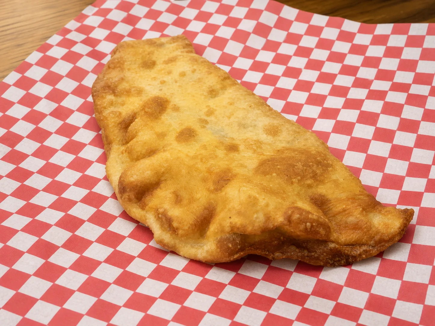 Golden fried classic calzone on red and white checkered paper