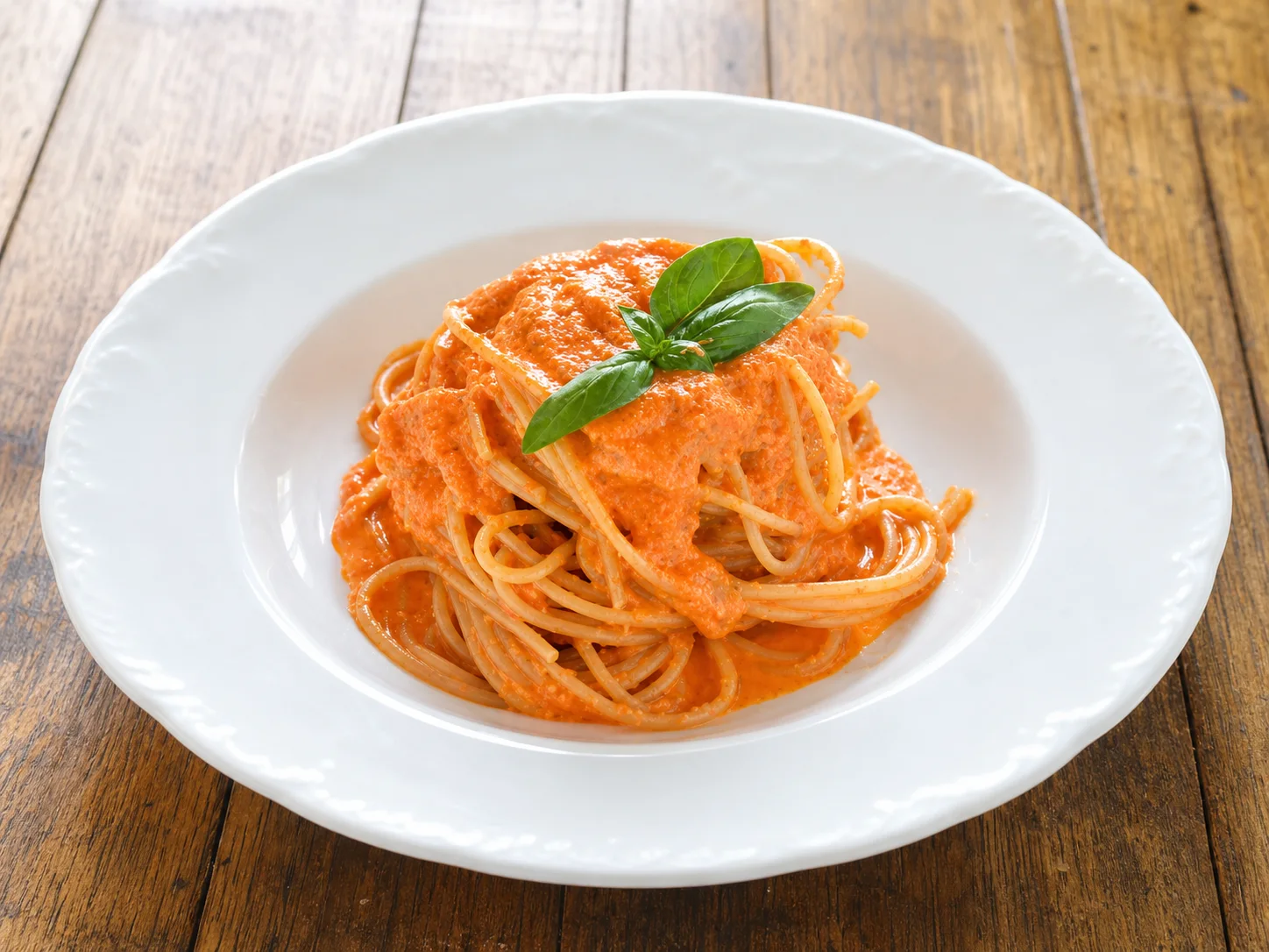 Spaghetti with creamy ricotta and tomato sauce in a white bowl